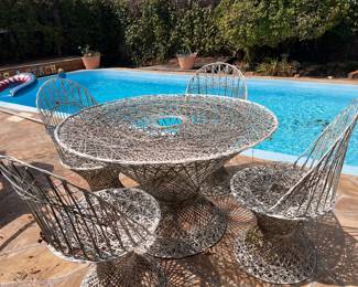 This mid-century modern Russell Woodard spun fiberglass dining set features a distinctive intricate weave design. The set includes a circular table and four matching chairs.