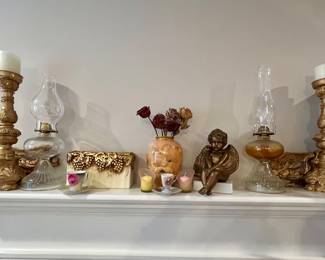 Traditional home décor featuring vintage oil lamps, ornate candlesticks, decorative pottery, cherub sculpture, and accent pieces.