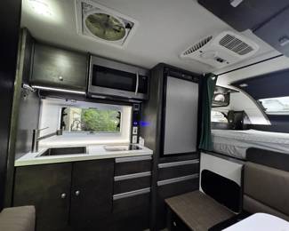nucamp truck camper kitchen with deep sink, microwave, stove top and mini fridge and freezer with plenty of extra storage space