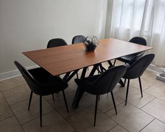   Stylish dining set in excellent condition, perfect for anyone looking to upgrade their dining space with a modern, sculptural look.  Dining Table — $500 OBO Rectangular table with a rich walnut-toned top and a striking black geometric trestle base — sturdy, well-built, and a real conversation piece. Comfortably seats 6. Dimensions: 79”L x 39.5”W x 29.5”H Smooth, well-maintained finish — some minor scratches and wear.  Black Faux Leather Chairs — $180 OBO each (6 available) Comfortable curved backs, faux leather upholstery, and sleek black metal legs. Sold as a set. Chairs’ faux fabric is worn down and needs to be upholstered.