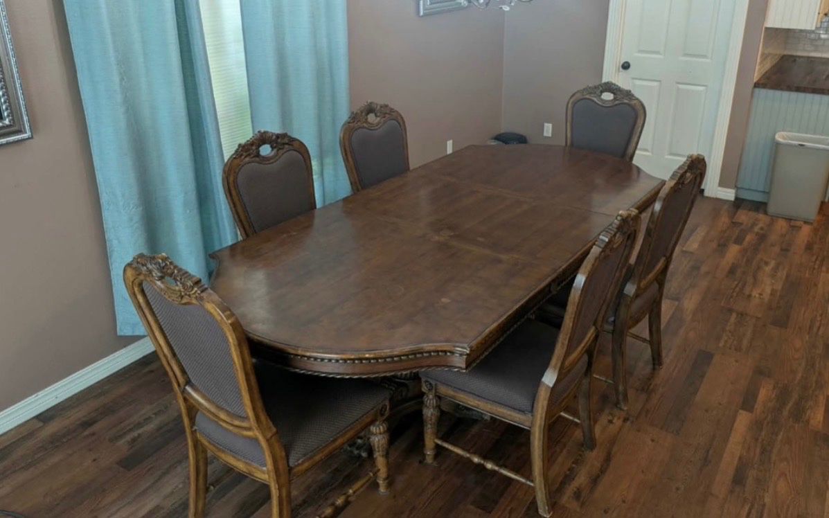 This premium 7-piece Ashley Furniture "Chateau Frontenac" formal dining set includes a large double-pedestal table with removable extension leaves and six upholstered high-back chairs, all beautifully adorned with intricate acanthus leaf and rope-twist carvings
