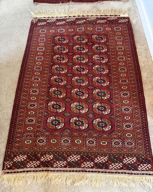 Dimensions: 3’5” x 6’0” Description: Hand knotted Bokhara rug.  Color: Features a signature red background, with repeating geometric gol pattern. (Medalion motif color pallet: rich warm red complimented by black, white/nave accent, high quality wool) Price: $400
