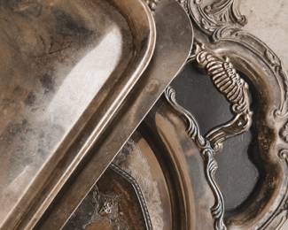 A varied collection of brass, silverplate, pewter, and other decorative metal pieces, including candlesticks, trays, bowls, vases, trivets, and small accents.