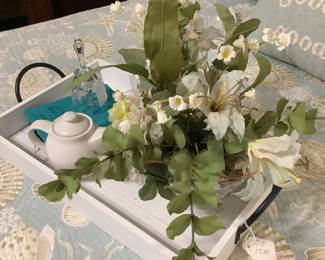 Tea set and flowers on white tray on bed.
