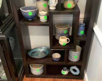 Lots of crocks, pottery pitchers on this black bookcase.