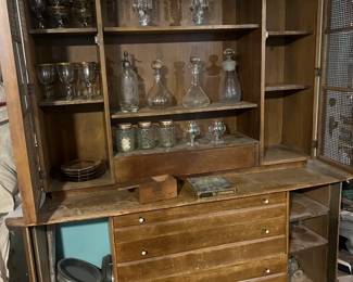 Vintage bar cabinet filled with wine glasses and various decanters