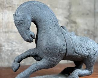 This lot features a 1961 Austin Productions Tang Dynasty style horse sculpture made of cast durastone that measures, 13” H x 18” W x 6” D.