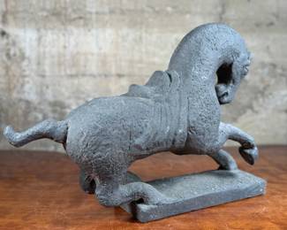 This lot features a 1961 Austin Productions Tang Dynasty style horse sculpture made of cast durastone that measures, 13” H x 18” W x 6” D.