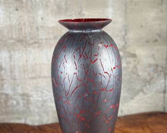 This lot features a stunning Italian glass vase with a lava effect by Dolbi Cashier. This vase measures, 20” H. Dolbi Cashier Italian glass vases, produced around 1993, are highly collectible pieces of art glass. They typically feature vibrant two-tone color palettes, like seeded aqua glass bodies with ruby red bases, and are known for their controlled bubble (bullicante) technique and statement silhouettes.