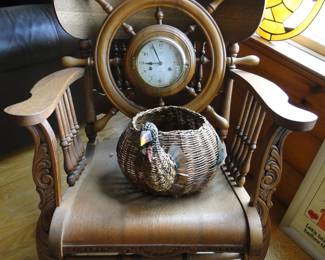 Classic large rocking chair and ships wheel clock and duck basket for collecting duck eggs.