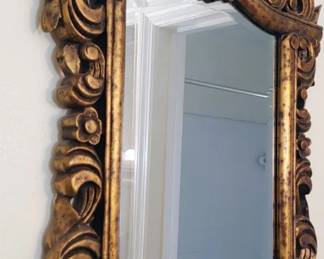ornate Italian Baroque-style carved giltwood wall mirror featuring deep acanthus leaf and scroll relief detailing.