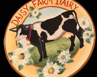 decorative ceramic plate featuring a charming black-and-white cow and white daisy accents, designed by artist Susan Winget