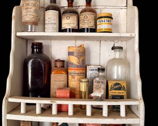 A huge collection of bottles displayed on hanging vintage wall shelves and corner shelves