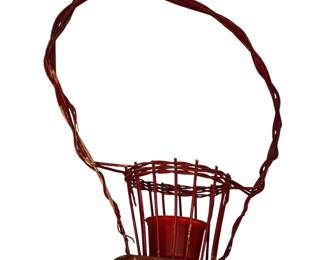 vintage red-painted twig or wicker basket with a tall arched gathering handle and a small cylindrical insert container at the base, resembling a decorative floral or cemetery piece