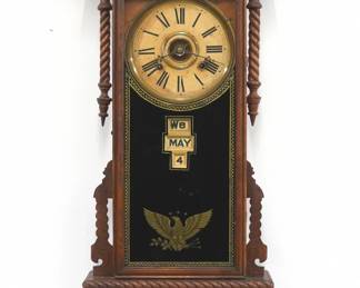 A late 19th century Gilbert Sharon model wall clock.  8-day time and strike movement with papered metal dial and Roman numerals, lower calendar mechanism with apertures indicating day, month and date.  Oak case with a shaped crest with turned rail over a single door single door with reverse painted glass flanked by turned half columns above a shaped lower drop with turned rails.  Interior paper label 50% intact but very dark.  Older refinishing with some wear, crack in drop, dial wear, running when cataloged.  37 1/2" high.  ESTIMATE $200-300
