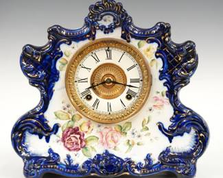A late 19th century Ansonia Dresden Extra model porcelain shelf clock made for the American Wringer Co... New York, No. 942.  8-day time and strike movement with enameled dial and Roman numerals.  Molded porcelain case with floral decoration and gilded detail on a Navy Blue background.  Minor wear, some crazing, running when cataloged.  12 1/2" high.  ESTIMATE $200-300