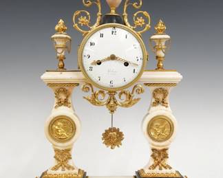 A late 18th/early 19th century French Portico clock by Michel-Francois Piolain, Paris (active from 1787). 8-day time and strike movement with silk thread suspension features a convex porcelain dial with Roman hour numerals within a ring of Arabic quarter numerals, pierced Fleur-De-Lis hands with concentric rings and a mask pendulum bob. The dial is marked "Piolain, a Paris". White Marble case with gilded Bronze detail portico form with upper urn finials and shaped columns on a rectangular base with inset Bronze panels. Minor wear, small losses, replaced center finial, running when cataloged. ESTIMATE $2,000-3,000