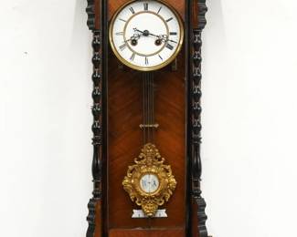 A turn of the century Vienna Regulator wall clock.  8-day time and strike movement with two part porcelain dial and Roman numerals, compensating pendulum and fancy gilded R/A bob.  Walnut case with Ebonized detail features a pediment top with carved crest over a door with arched glass flanked by turned pilasters over a shaped drop with turned finials.  Older finish with minor wear, running when cataloged.  31 1/2" high.  ESTIMATE $300-400