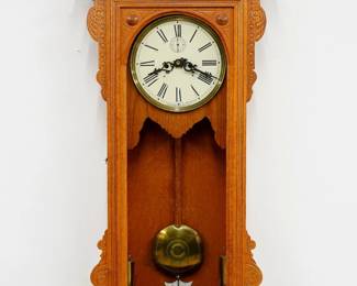 A late 19th century Waterbury model 57 wall clock.  8-day dual weight time only movement with dead beat escapement and maintaining power, painted metal dial and Roman numerals, subsidiary seconds.  Oak case with carved detail features and arched crest on a molded crown over a door with arched glass and reeded frame over a bracket drop with lower gallery.  Paper label inside 90% intact.  Cleaned finish with minor wear, some dial crazing, running when cataloged.  48" high.  ESTIMATE $800-1,200