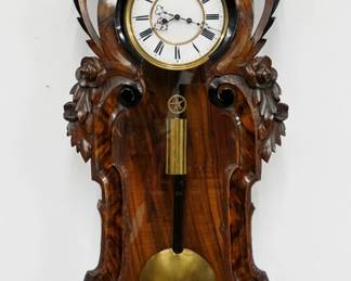 An unusual 19th century Vienna Regulator wall clock.  8-day weight driven time side/spring driven strike side movement with quarter hour Grand Sonnerie striking and a two-part porcelain dial with Roman numerals, within a molded Brass bezel.  Original grain painted case with Ebonized detail features a carved crest and arched top over a serpentine door with carved floral design and a shaped lower drop with carved skirt.  Includes the original swing handle crank/key which winds both arbors.  Original finish, minor wear, fine dial hairlines at 11:00, running when cataloged.  42 3/4" high overall.  ESTIMATE $600-800