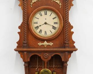A late 19th century Waterbury Study No. 7 model wall clock.  8-day weight driven time and strike movement with papered metal dial and Roman numerals.  Oak case with applied gilded metal decoration features a shaped crest and turned finials over a circular dial door flanked by rope twist columns and a lower open bracket drop.  Paper labels on back 80% intact.  Older finish with some wear, dial re-papered, running when cataloged.  30" high plus weight drop.  ESTIMATE $300-500