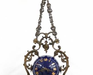 An unusual late 19th century Lenzkirch Suspended Wall clock.  8-day spring driven time and strike movement with platform escapement,  Gold painted Roman numerals and fancy filigree hands, serial #774221indicates a production date of 1886.  Spherical Cobalt Blue porcelain case with scrolled foliate frame is suspended by four fancy cast Brass chains and a fanciful Dragon wall bracket.  Slight wear, one replaced screw fitting, running when cataloged.  26 1/2" high overall. ESTIMATE $2,000-3,000