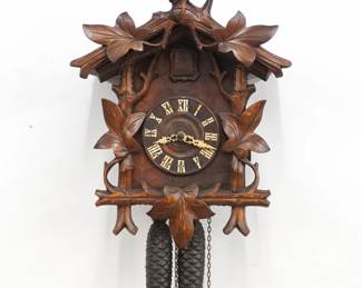 An early 20th century German Black Forest Cuckoo wall clock.  30-hr Brass time and strike two weight movement with wooden dial and applied Roman numerals.  Walnut case with hand carved detail features aRooster crest on a body with vine and foliage detail.  Old finish with minor wear, running when cataloged.  25 1/2" high plus weight drop.  ESTIMATE $300-500