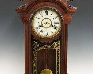 A late 19th century New Haven Lena model shelf clock.  8-day time and strike movement with painted metal dial and Roman numerals.  Walnut case with turned finial on a shaped crest above an arched molded door with reverse painted glass on a molded base.  Paper label on back 80 % intact.  Old finish with some wear, dial wear, paint flaking on door glass,  running when cataloged.  36 3/4" high.  ESTIMATE $200-300