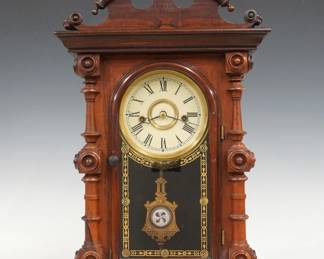 A 19th century E. N. Welch Cary V.P. model Victorian shelf clock. 8-day time and strike movement with painted metal dial and Roman numerals, fancy pendulum with glass insert. Rosewood case with scalloped top and turned finials above a single arched door with stenciled glass, flanked by turned columns on a molded base. No label. Older finish with minor wear, re-painted dial, running when cataloged. 20 1/2" high. ESTIMATE $400-600
