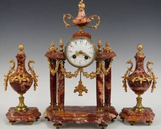 A late 19th century French 3 pc mantel clock set by Societe Clusienne in Cluses, France. 8-day time and strike movement with convex porcelain dial, Arabic numerals painted floral garlands and fancy Brass filigree hand, serial #5695. Figured Rouge marble case and matching garniture urns and gold patinated mounts features an urn finial over a Brass movement housing supported by four turned columns with floral swags on a shaped molded base. Good condition with slight wear, running when cataloged. Up to 16 1/4" high. ESTIMATE $400-600
