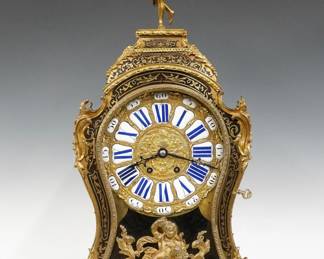 A late 19th century French Louis XV style Boulle bracket clock.  8-day time and strike movement with a gilded cast Brass dial with porcelain markers, Blue Roman hour and Black outer Arabic minute numerals, serial #381.  Red and Black lacquer case with Boulle decoration features a shaped top and sides surmounted by a cast Bronze finial depicting a Trumpeting Angel, over a single shaped Brass door with a Cherub on scrolled foliate feet, hand chased gilded Bronze mounts throughout, Boulle decoration extends to the inner floor and rear door panels.  Some wear and minor damage, running when cataloged.  28 1/2" high.  ESTIMATE $2,000-3,000
