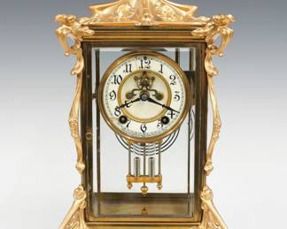 A turn of the century New Haven Thames model crystal regulator. 8-day spring driven time and strike movement with two part porcelain dial, visible escapement and Arabic numerals with a faux Mercury pendulum. Art Nouveau Brass case with scrolled floral detail, beveled glass doors and sides on a scrolled base. Minor wear, dial hairlines and chip at 7:30, running when cataloged. 15 3/4" high overall. ESTIMATE $300-400