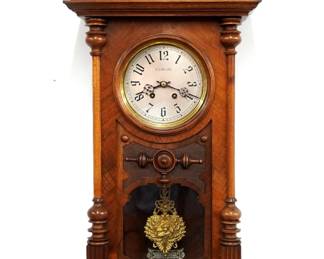 An early 20th century Lenzkirch wall clock retailed by G. Bornand (Marseille, France).  8-day time and strike movement with Silvered dial and Arabic numerals, bi-metallic compensating pendulum and fancy cast Cherub bob, serial # 1 million 591237 indicates a production date of 1908.  Walnut case with arched crest and turned finial over a deeply carved shell, door with circular dial glass and shaped lower flanked by turned pilasters over a shaped drop and turned finials.  Original polished finish with minor wear, running when cataloged.  42 1/2" high.  ESTIMATE $800-1,200