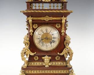 A late 19th century Lenzkirch Table clock.  8-day spring driven time and strike movement with Silvered dial, etched center and Roman numerals, serial #521945 indicates a production date of 1880.  Oak case with molded detail features gilded cast Brass finials, appliques and gallery over a circular dial door with convex glass, Gryphon corner posts, Lion's Mask side plates, reticulated foliate moldings and Lion's Paw feet.  Older finish with minor wear, lacks center post on gallery, running when cataloged.  19 3/4" high overall. ESTIMATE $800-1,200