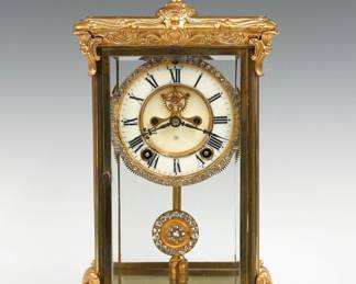 A turn of the century Ansonia Crown model crystal regulator. 8-day spring driven time and strike movement with two part porcelain dial, visible escapement and Roman numerals with applied brilliants on bezel and pendulum. Louis XV Style Gilded Brass case with urn finial, scrolled foliate detail, beveled glass doors and sides on a scrolled base with shaped feet. Re-painted with minor wear, faint dial hairline, running when cataloged. 15 1/4" high overall. ESTIMATE $300-500