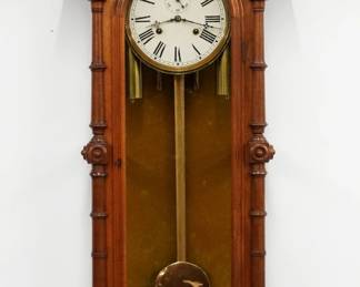 A 19th century E. N. Welch Patti No. 7 model Victorian wall clock. 8-day dual weight driven time only movement with painted metal dial and Roman numerals, small subsidiary seconds dial and a gilded wood pendulum stick. Walnut case with arched top and turned finials above a single arched door flanked by turned columns and two piece side glasses above a shaped drop with turned finials. Older refinishing with minor wear, refinished back with upholstered interior, running when cataloged. 46 1/4" high. ESTIMATE $1,000-2,000