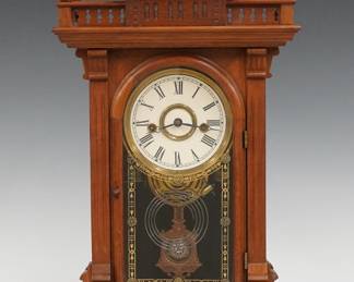A 19th century E. N. Welch Scalchi model Victorian shelf clock. 8-day time and strike movement with painted metal dial and Roman numerals, fancy pendulum with glass insert. Walnut case with shaped gallery top and turned finials above a single arched door with stenciled glass, flanked by fluted pilasters on a molded base. Paper label on back 50%. Older finish with minor wear, re-painted dial, running when cataloged. 19 1/4" high. ESTIMATE $300-400