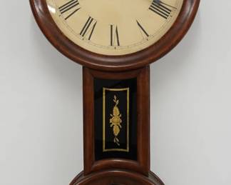 A mid 19th century "Baltimore" Banjo clock attributed to George D. Hatch, North Attleboro, MA. 8-day weight driven time only movement with painted metal dial and Roman numerals, wooden pendulum stick with detachable Brass bob. Mixed wood case with traces of original "Rosewood" graining, circular upper and lower doors, reverse painted throat and lower door "Regulator" glasses with gilded detail. Cleaned finish with minor wear, replaced dial, running when cataloged. 33" high. ESTIMATE $600-800