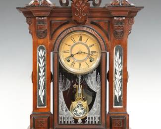 A late 19th century Gilbert Amphion Model Parlor clock.  8-day time and strike movement with papered metal dial and Roman numerals.  Walnut case with a shaped crest over a single arched door with stenciled glass and inset mirrored cut glass panels on a molded base with Ebonized detail.  Paper label on back 60% intact.  Original finish with Ebonized detail, minor wear, some dial wear, slight loss to silvering, running when cataloged.  25 3/4" high.  ESTIMATE $400-600