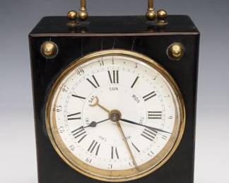A turn of the century French calendar desk clock. 8-day time only movement with platform escapement and porcelain dial with Roman numerals, additional indicators for date and day of the week. Ebonized wooden case with Brass swing handle and applied details. Minor wear, running when cataloged. 7 1/4" high overall. ESTIMATE $200-300