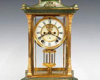 A turn of the century Ansonia crystal regulator No. 2 model clock. 8-day spring driven time and strike movement with two part porcelain dial, visible escapement and Roman numerals with faux Mercury pendulum. Louis XV Style Brass case with porcelain crown and base and gilded detail, beveled glass doors and sides on a scrolled base with shaped feet. Minor wear, running when cataloged. 17 1/4" high overall. ESTIMATE $600-800