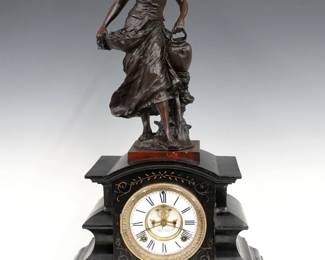 A late 19th century Ansonia cast Iron figural mantel clock.  8-day time and strike movement with visible escapement and two piece White porcelain dial with Roman numerals, marked "Ansonia Clock Co. Patented".  Black enameled cast iron case surmounted by a patinated Spelter figure of a young woman, features a  rounded top over a body with shaped pilasters on a molded plinth base with incised detail.  Some surface wear, running when cataloged.  26 1/4" high.  ESTIMATE $400-600
