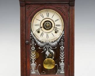 A late 19th century Bridgeport Brass Co. Victorian shelf clock.  8-day time, strike and alarm movement with papered metal dial and Roman numerals.  Walnut case with a molded top and turned finials over an arched door with stenciled glass flanked by fluted pilasters on a molded base.  Original finish with some wear, dial wear, running when cataloged.  20 3/4" high.  ESTIMATE $100-150