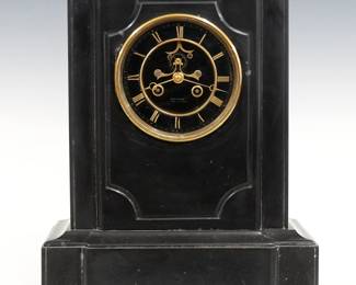 A 19th century French mantel clock by Samuel Marti, Paris, retailed by Gauthier, A Bar Sur Aube.  8-day time and strike movement with visible escapement and two piece Black porcelain dial with Gold Roman numerals, serial #3163.  Black marble case with a shaped top over a molded body on a molded plinth base.  Minor wear, some tiny edge flakes, running when cataloged.  15" high.  ESTIMATE $400-600