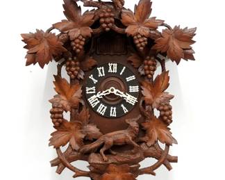 A 20th century German Black Forest Cuckoo wall clock with Music box which plays on the hour, including "In the most beautiful meadow", "In the green forest where the Thrush sings" and "Now I go to the little well".  30-hr Brass time and strike three weight movement with Cuckoo and Musician, wooden dial and applied Roman numerals.  Mixed wood case with carved detail features a Raven crest over a body with Fox and Grapes motif on dial surround.  Paper tune label onside 80% intact.  Older finish with minor wear, glued repair to crest, running when cataloged.  30" high plus weight drop.  ESTIMATE $600-800
