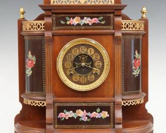 A turn of the century Ansonia Chippendale model mantel clock.  8-day time and strike movement with a papered metal dial, visible escapement and Arabic numerals.  Mahogany case with painted floral decoration, features a galleried top and sides surmounted by Brass finials above a circular Brass bezel, flanked by curved side panels over open shelves on a molded base with Brass feet.  Refinished with minor wear, re-painted decoration, running when cataloged.  19 1/2" high.  ESTIMATE $200-300