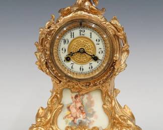 A turn of the century Waterbury Seine model mantel clock. 8-day spring driven time and strike movement with flat porcelain dial and Arabic numerals with embossed Brass center. Louis XV Style cast spelter case with foliate detail and inset porcelain panel on a scrolled base. Restored Gold finish with slight wear, running when cataloged. 13" high overall. ESTIMATE $100-150