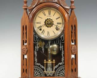 A late 19th century Gilbert Turret model shelf clock.  8-day time, strike and alarm movement with papered metal dial and Roman numerals.  Walnut case with carved crest and turned finials above a single door with stenciled glass in a molded frame flanked by pierced pilasters with rosettes on a plinth base.  Paper label on back 10 % intact.  Refinished with minor wear, re-papered dial, running when cataloged.  21 1/2" high.  ESTIMATE $100-150