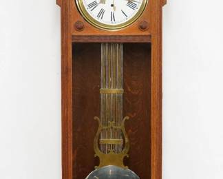 A turn of the century Waterbury Regulator No. 60 model wall clock.  8-day weight driven time only movement with dead beat escapement, maintaining power and 12" porcelain dial and Roman numerals, sweep seconds and a Lyre pendulum.  Oak case with carved detail features a shaped crest and decorative frieze over a single long door with circular dial glass and rectangular lower over a scrolled drop with turned finials.  Older refinishing with some wear, restored top crest and drop, running when cataloged.  75" high overall.  ESTIMATE $1,000-2,000