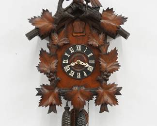 An early 20th century Black Forest style Cuckoo wall clock by the American Cuckoo Clock Co.  30-hr Brass time and strike two weight movement with wooden dial and applied Roman numerals.  Walnut case with hand carved detail features an Eagle crest on a body with grape vine motif.  Paper label on back 60% intact.  Old finish with minor wear, running when cataloged.  25" high plus weight drop.  ESTIMATE $300-500
